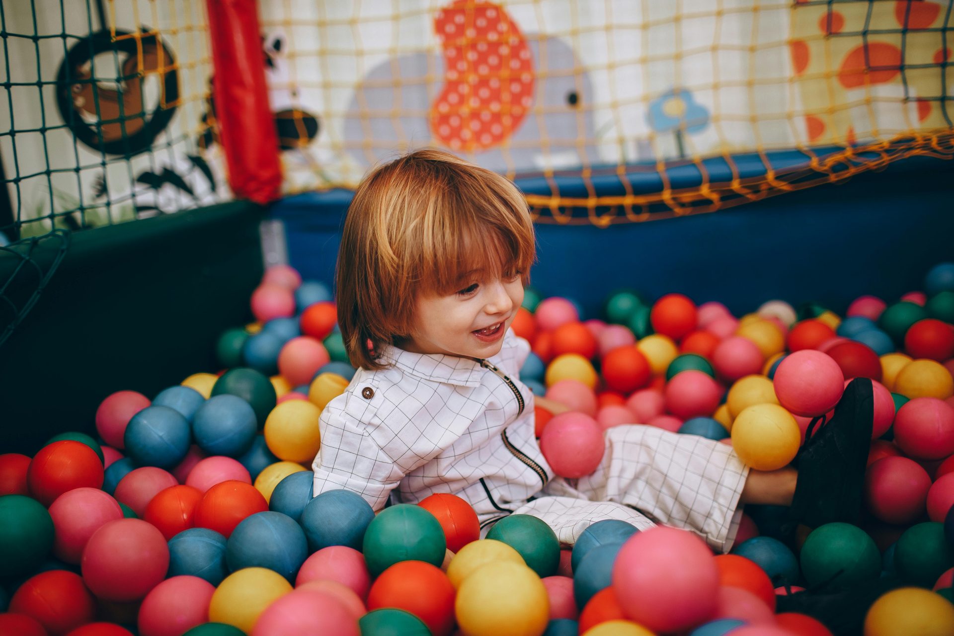 Una niña alegre que disfruta de tiempo de juego en un colorido hoyo de pelota de interior.